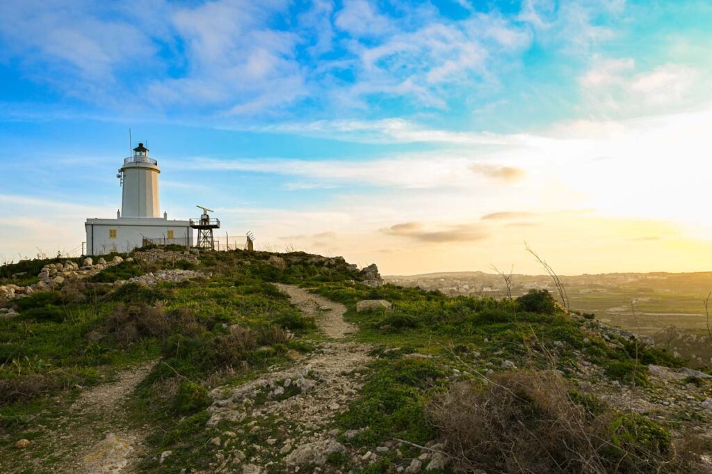 the gozo lighthouse during sunset and surrounding green fields